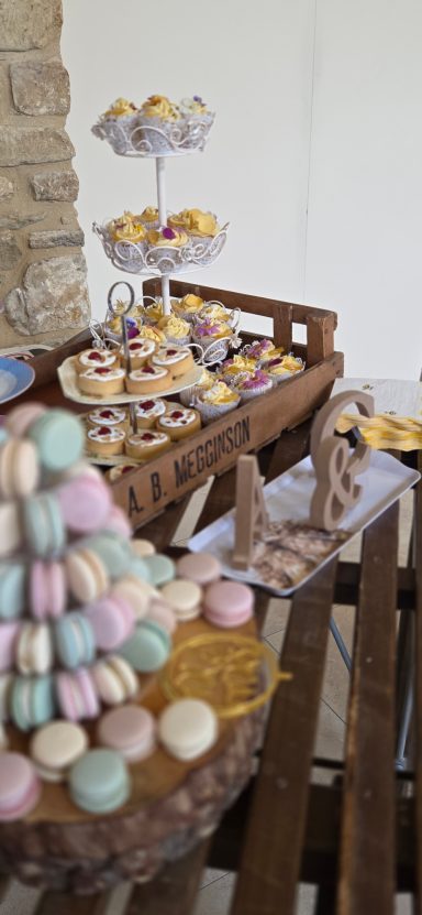 A platter of colourful desserts including macarons and cupcakes on a wooden display.